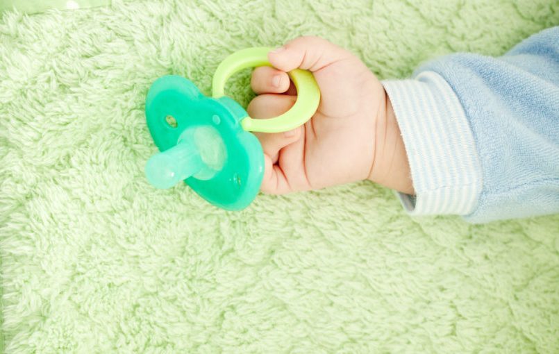 Chupón verde en mano de bebé